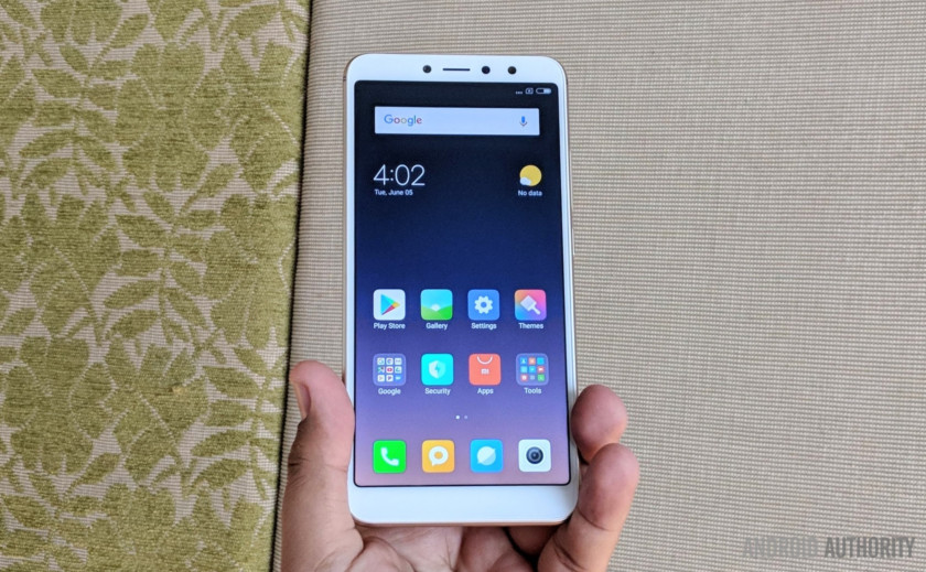  Xiaomi Redim Y2 سفید در کسی دست، مقابل پرده وزن. 